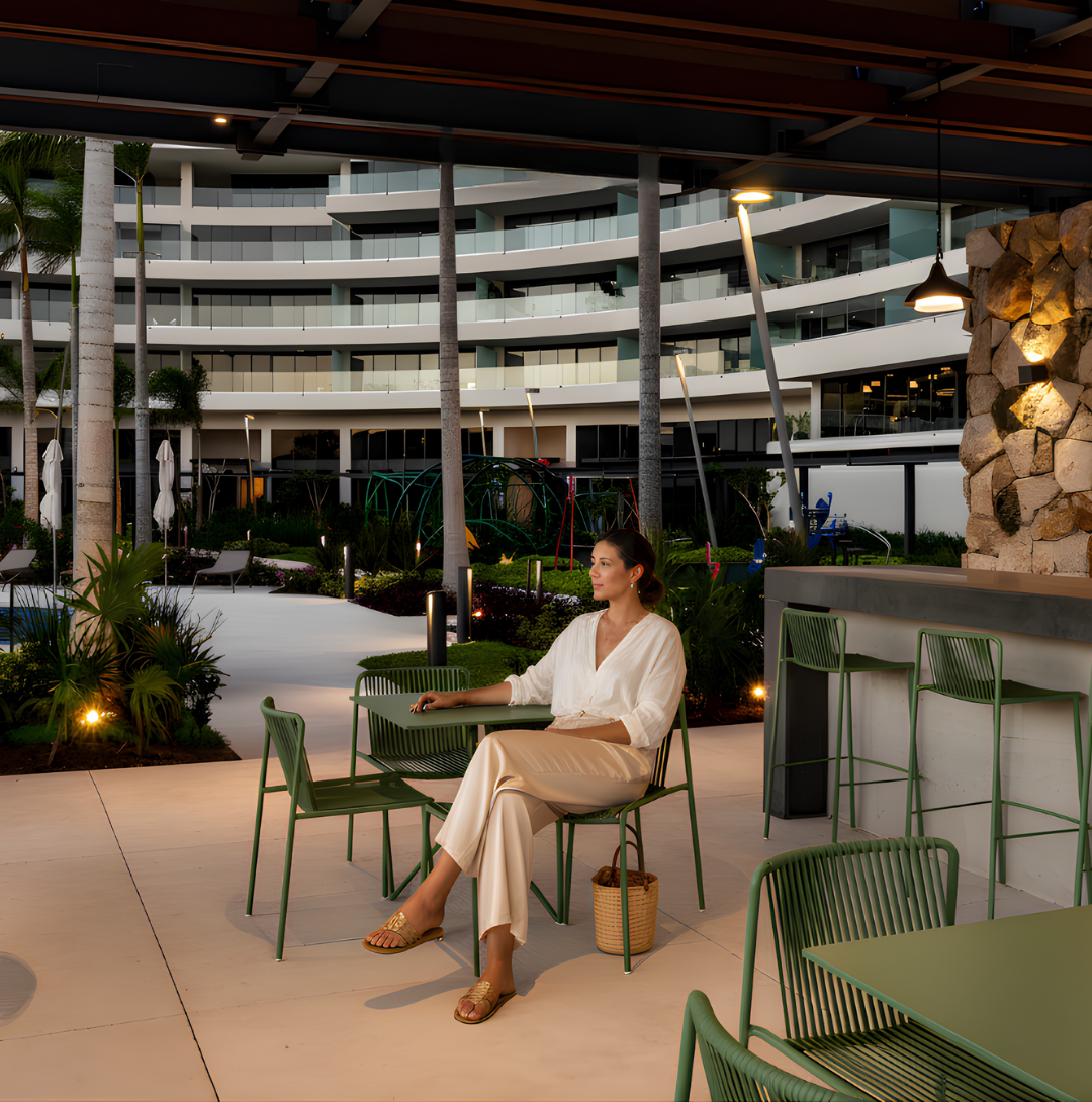 Mujer disfrutando área común en departamentos de lujo en Meriden Cabo Norte, Mérida, con jardines, amenidades premium y arquitectura contemporánea